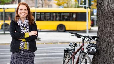 A woman stands in front of a tram with her arms crossed