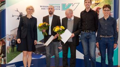 People standing in front of a screen, on the left a woman and then 5 men