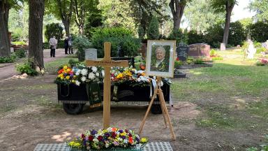 auf dem Bild ist ein frisches Grab mit Blumen zu sehen