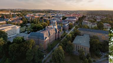 Aerial view of the university grounds of the TU Dresden, bottom right a portrait of a man with short hair