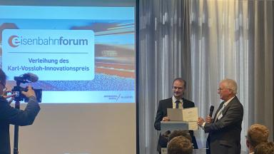 2 Männer auf einem Podium mit Preisübergabe