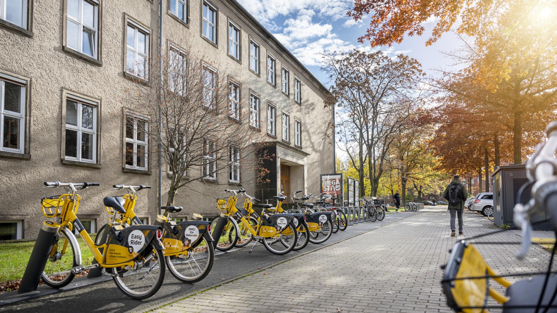 Außensicht auf ein TUD-Gebäude mit gelben Leihrädern davor.