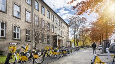 Exterior view of a TUD building with yellow rental bikes in front of it.