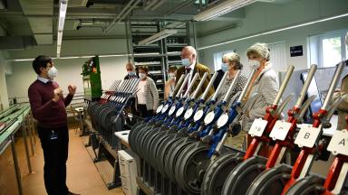 People in a railway laboratory. In the foreground, control levers.