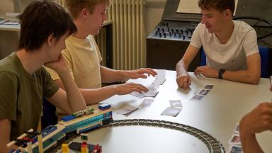 Three students sort cards on a table