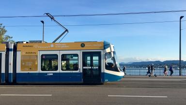 A blue and white tram is crossing a bridge in Zurich.