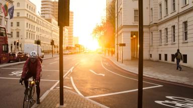 Bicyclist with helmet on road in front of sunrise