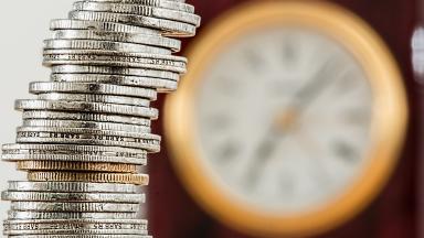 A tower of money coins and a clock in the background