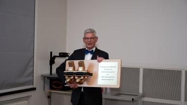 Ein älterer Mann mit Fliege hält ein Geschenk