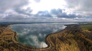 Blick über eine Seenlandschaft im Herbst. Straßen führen um den See.