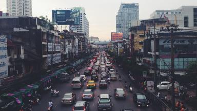 Häuserschluchten einer Großstadt in Indien mit Verkehrsstau, Autos, Mofas.