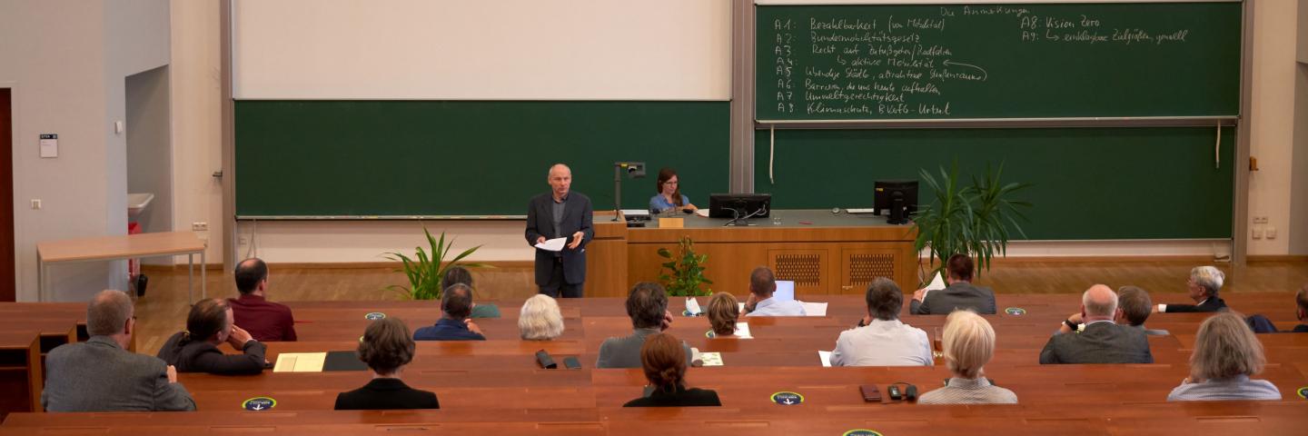 A lecture hall with people sitting at intervals.