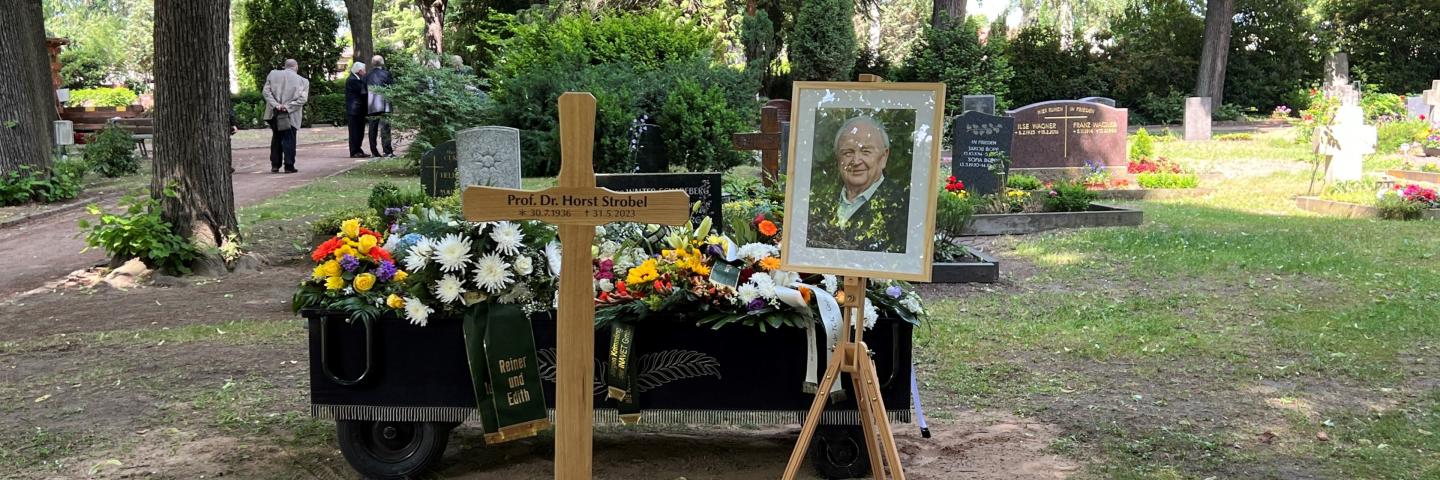 auf dem Bild ist ein frisches Grab mit Blumen zu sehen