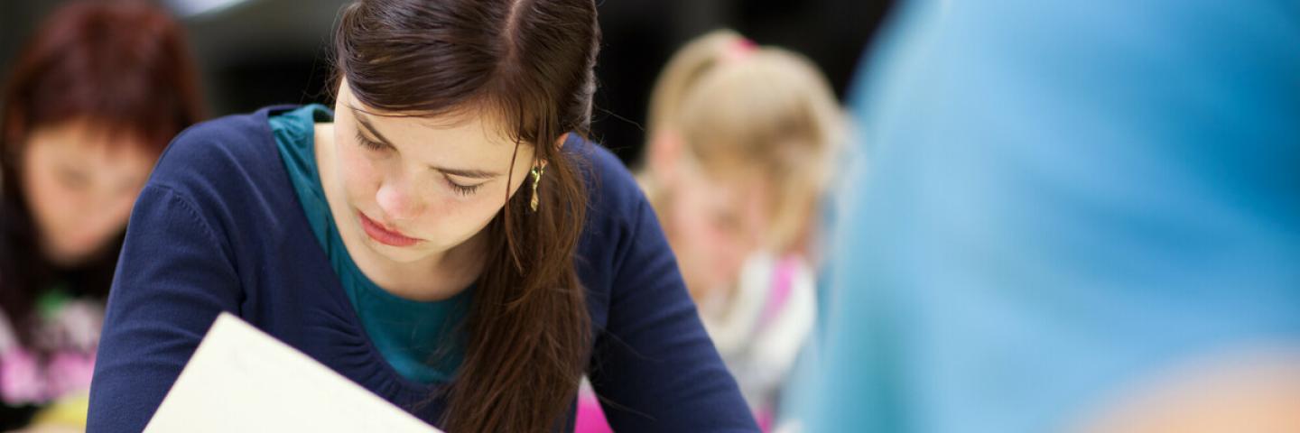 The photo shows concentrated students writing an exam.