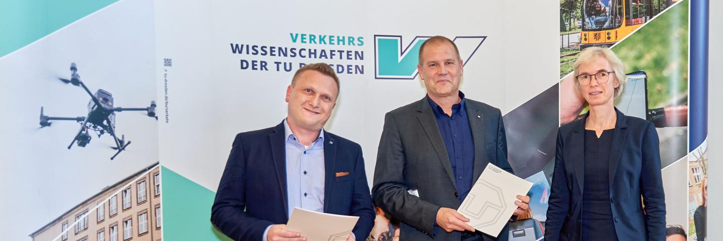 3 Menschen vor einer Fotowand