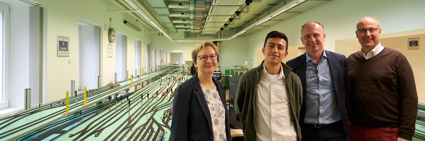 A woman, a student and two men stand in the railway operation laboratory at TU Dresden