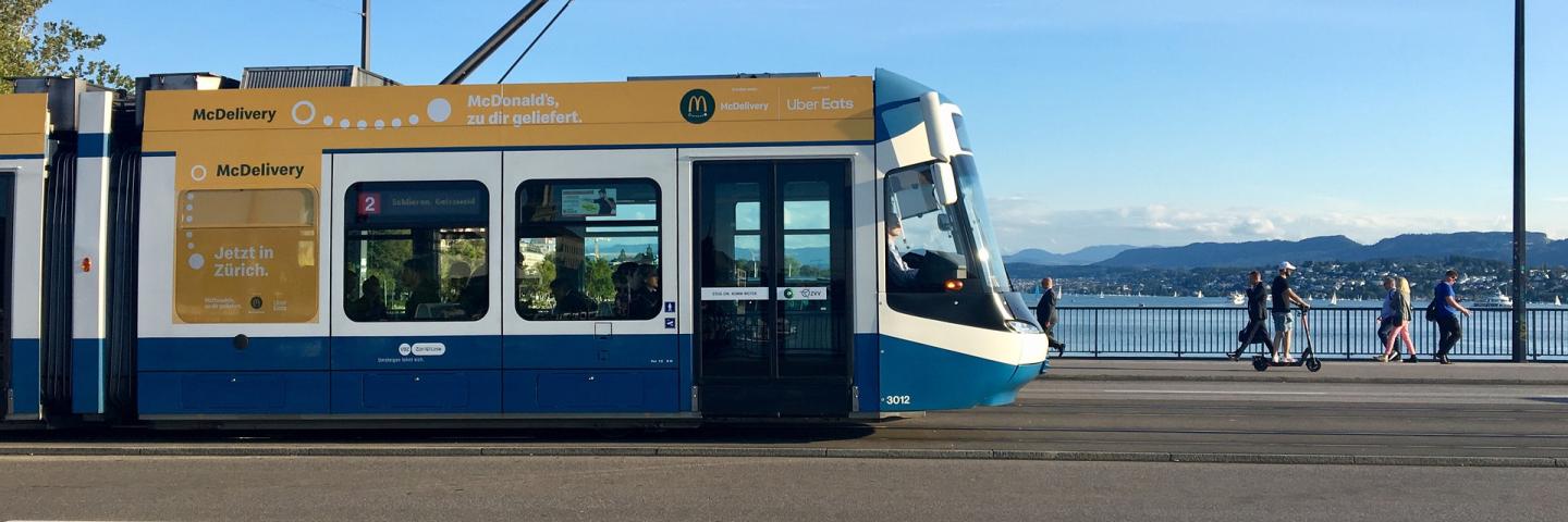 A blue and white tram is crossing a bridge in Zurich.