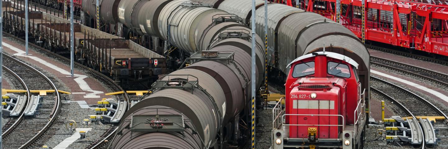 A marshalling yard with many trains with wagons. A locomotive is pulling a train.