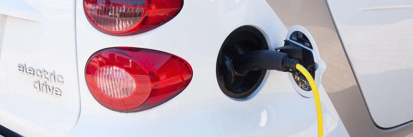 A small electric car refuelling at a charging station
