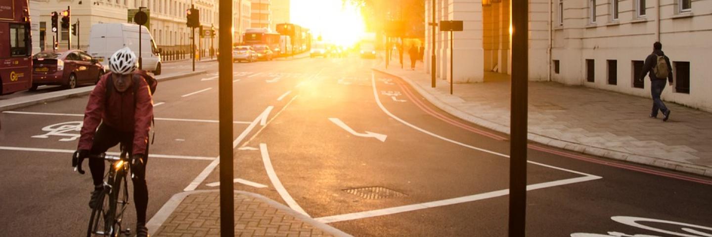Bicyclist with helmet on road in front of sunrise