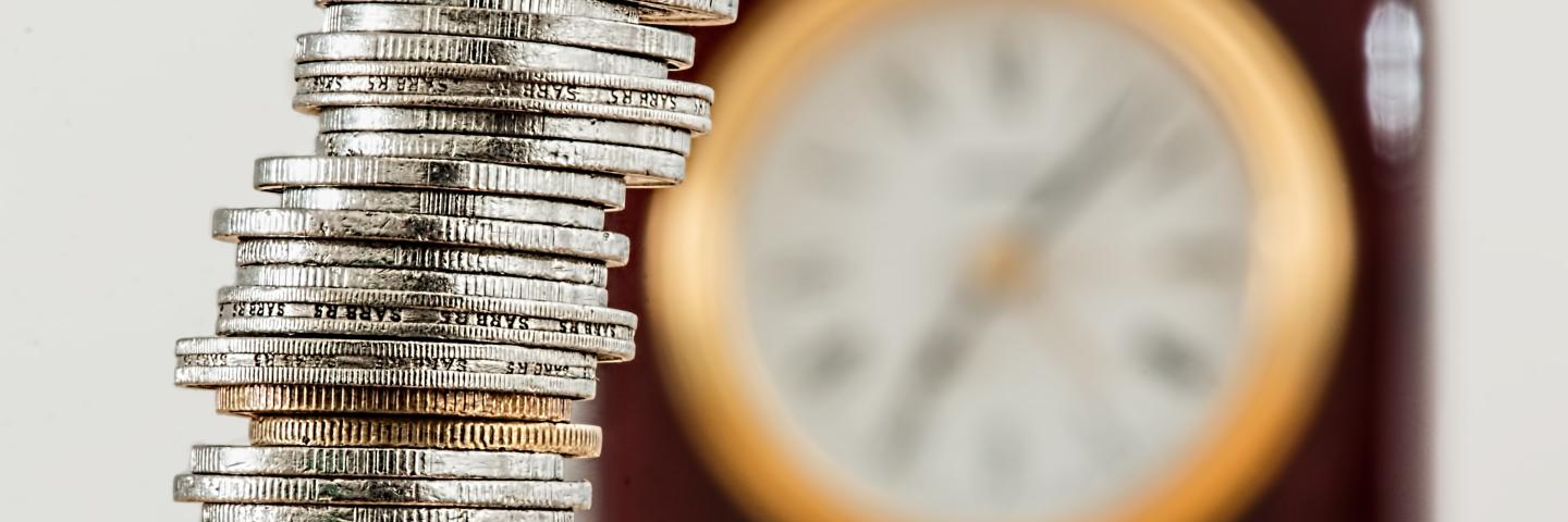 A tower of money coins and a clock in the background