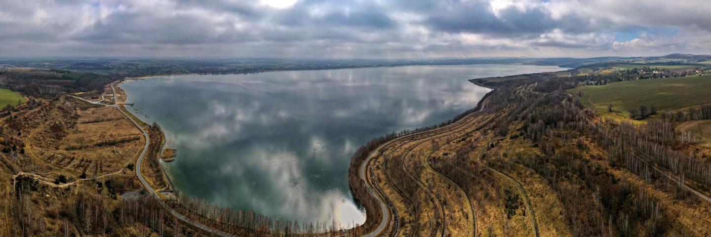 Blick über eine Seenlandschaft im Herbst. Straßen führen um den See.