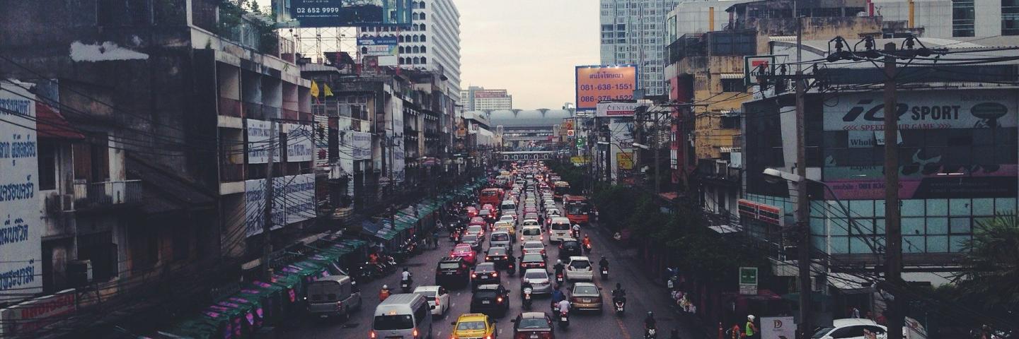 Häuserschluchten einer Großstadt in Indien mit Verkehrsstau, Autos, Mofas.